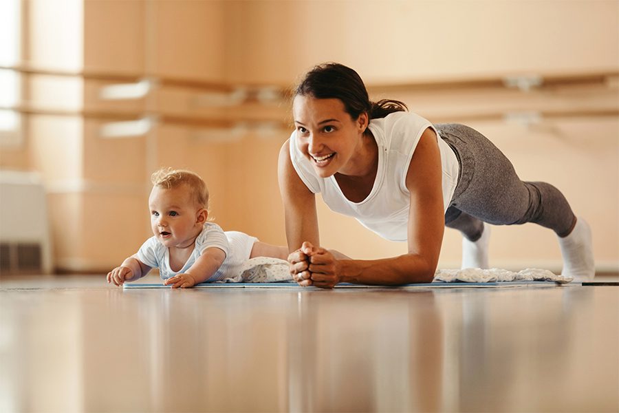 Employee Benefits - Mother and Baby Doing Plank Exercises in Health Club