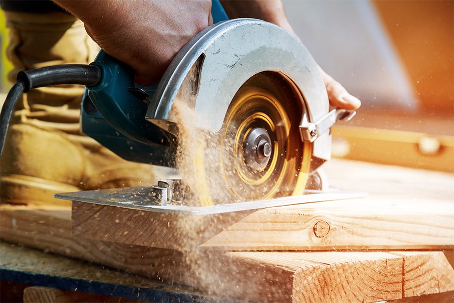 Specialized Business Insurance - Closeup of Building Contractor Working with Circular Saw to Cut Boards on a New Home Construction Project